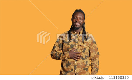 Confident male model laughing at jokes on camera, feeling happy and enjoying good times in studio. African american man acting silly and amusing over memes, having fun with laughs. 113168330