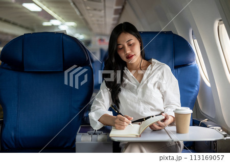 An elegant Asian businesswoman is on a plane, flying to another city for a business meeting. 113169057