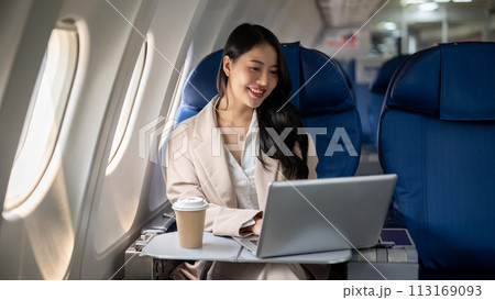 An attractive Asian female CEO is working on her laptop during the flight for her business trip. An attractive Asian female CEO is working on her laptop during the flight for her business trip. 113169093