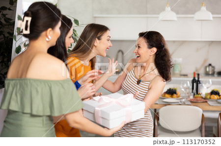Three women have arrived for birthday celebration and presenting gift to birthday woman 113170352