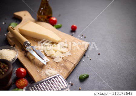 Piece of Traditional Italian Parmesan Hard cheese on a wooden cutting board at domestic kitchen Piece of Traditional Italian Parmesan Hard cheese on a wooden cutting board at domestic kitchen 113172642