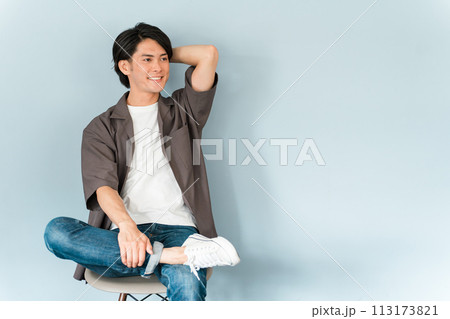 椅子に座るスニーカーとジーンズ姿のさわやかな男性 113173821