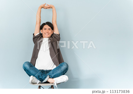 椅子に座るスニーカーとジーンズ姿のさわやかな男性 椅子に座るスニーカーとジーンズ姿のさわやかな男性 113173836