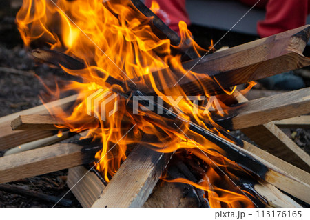 A fire burns in a campfire with a red fire in the background. 113176165