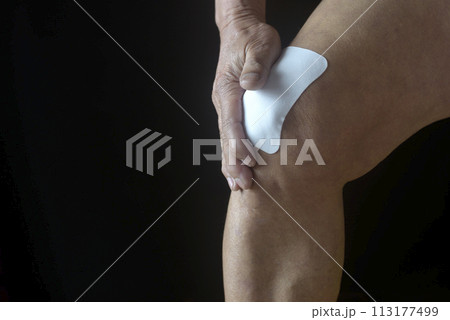 膝痛で苦しむ老人の膝に湿布薬 膝痛で苦しむ老人の膝に湿布薬 113177499