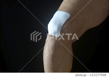 膝痛で苦しむ老人の膝に湿布薬 膝痛で苦しむ老人の膝に湿布薬 113177500