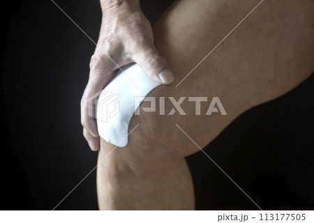 膝痛で苦しむ老人の膝に湿布薬 113177505