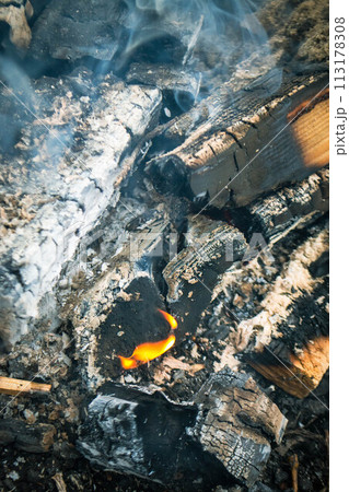 A fire burns in a campfire with a red fire in the background. A fire burns in a campfire with a red fire in the background. 113178308