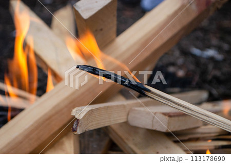 A fire burns in a campfire with a red fire in the background. 113178690