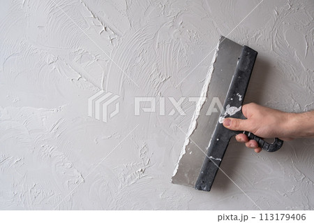Applying decorative putty. White abstract texture of surface covered with putty 113179406
