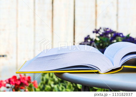 Opened book on table in flower summer garden 113182037