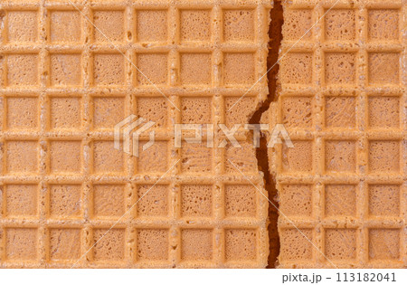 Broken spelt waffle with grid pattern as background 113182041