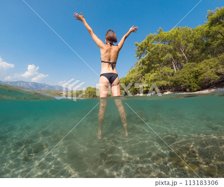 Woman on tropical vacation paradise on sea. Summer sea joy in Turkish seacoast, beaches along Lycian Way, Turkish Riviera. Asian female underwater and turquoise ocean around. Woman on tropical vacation paradise on sea. Summer sea joy in Turkish seacoast, beaches along Lycian Way, Turkish Riviera. Asian female underwater and turquoise ocean around. 113183306