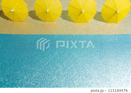Abstract beach with glitter paper sand and water and cocktail umbrellas. Summer aesthetic mockup template background on a tropical beach holiday Abstract beach with glitter paper sand and water and cocktail umbrellas. Summer aesthetic mockup template background on a tropical beach holiday 113184476