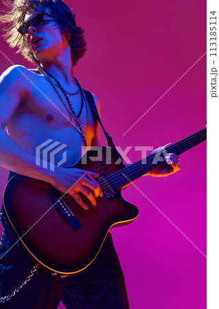 Talented and artistic young man, shirtless musician playing electric guitar against pink background in neon light Talented and artistic young man, shirtless musician playing electric guitar against pink background in neon light 113185114