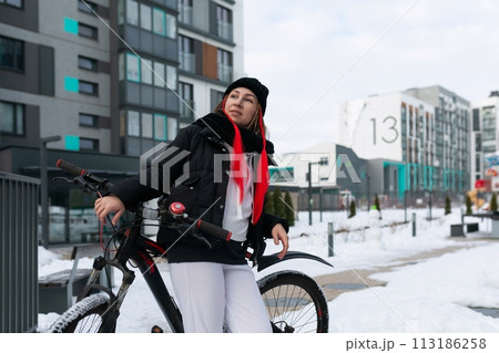 European woman in winter clothes riding a bicycle in winter 113186258
