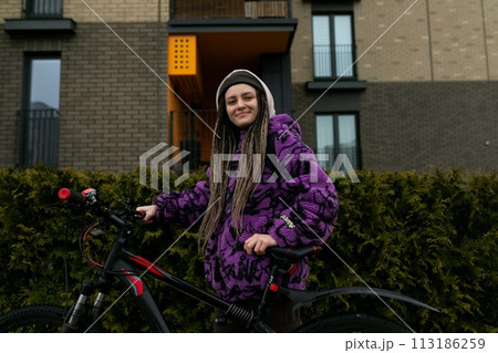 Bicycle rental concept. Young woman with dreadlocks holding a bicycle 113186259