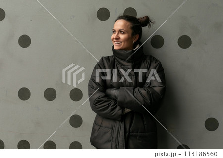 Portrait of a happy cute brunette woman against a black wall 113186560