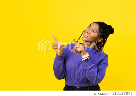 Young Woman Pointing Upwards on Yellow Background 113187073