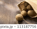 木製テーブルに置かれた麻袋のジャガイモ 113187756