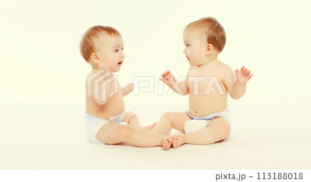 Two twin babies in diapers sitting on the floor on white studio background 113188018