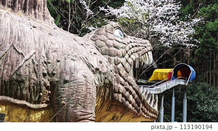 桜の名所の山中渓の近くにあるわんぱく王国の巨大な恐竜の滑り台と桜 桜の名所の山中渓の近くにあるわんぱく王国の巨大な恐竜の滑り台と桜 113190194