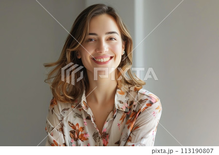 A woman with long brown hair and a floral shirt is smiling 113190807
