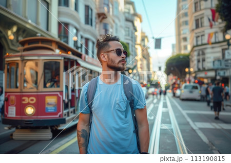 A man in a blue shirt stands on a city street next to a trolley 113190815