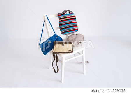 Assorted Handmade Crochet Bags on White Wooden Chair 113191384