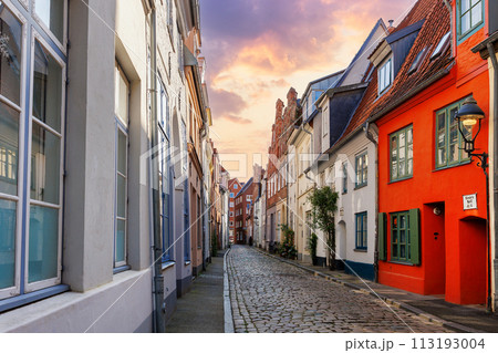 Scenic view old narrow european german Lubeck town street  red brick ancient houses vintage iron stained glass lamp lantern on wall. Cityscape UNESCO heritage city altstadt Germany travel destination 113193004