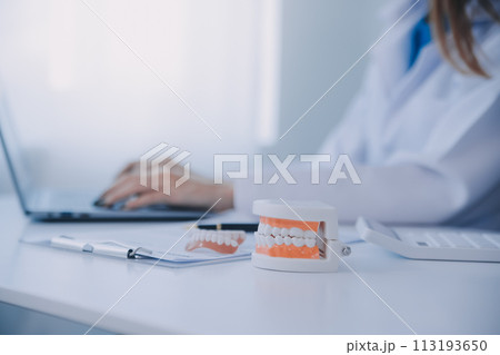 Dentists are discussing dental problems at report x-ray image on laptop screen to patients. 113193650