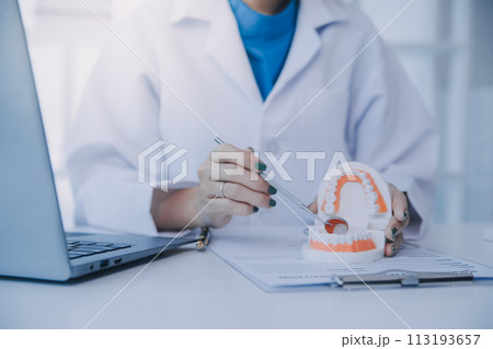 Dentists are discussing dental problems at report x-ray image on laptop screen to patients. 113193657