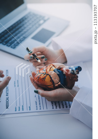 Doctor explaining heart to elderly patient. Doctor explaining the heart model. Doctors pen point to a model of the heart Doctor explaining heart to elderly patient. Doctor explaining the heart model. Doctors pen point to a model of the heart 113193707
