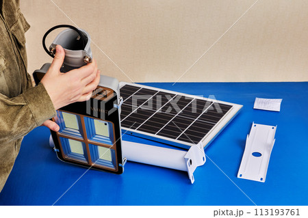 Green technology for outdoor lighting, LED light with solar panel for use in private home, parts of device for DIY assembly are on blue table. 113193761
