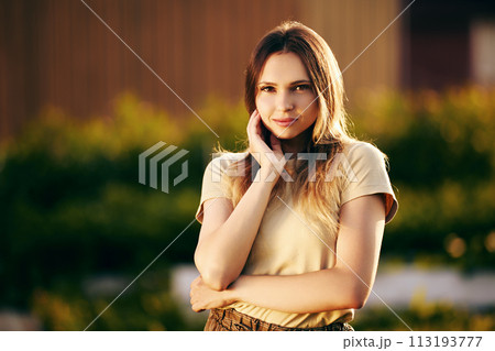 Sunset light on face of beautiful young woman, half-length portrait of white slender female about 20 years old on summer evening in countryside. Sunset light on face of beautiful young woman, half-length portrait of white slender female about 20 years old on summer evening in countryside. 113193777