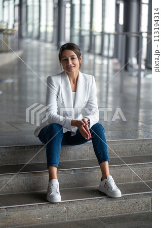 Smiling relaxed pretty woman sitting on the steps Smiling relaxed pretty woman sitting on the steps 113194314