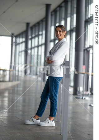 Confident elegant woman in white jacket standing in the premises with big windows Confident elegant woman in white jacket standing in the premises with big windows 113194335