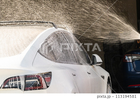 Efficiently cleaning an electric car in the comfort of a suburban driveway, combining eco-consciousness with practicality. Efficiently cleaning an electric car in the comfort of a suburban driveway, combining eco-consciousness with practicality. 113194581
