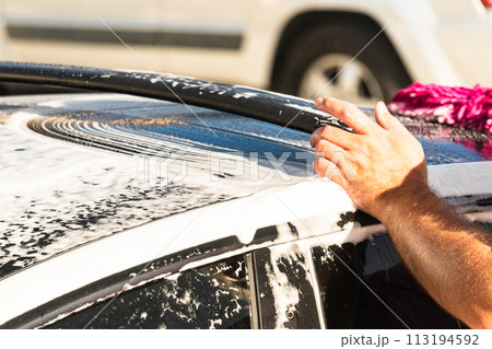 Efficiently cleaning an electric car in the comfort of a suburban driveway, combining eco-consciousness with practicality. Efficiently cleaning an electric car in the comfort of a suburban driveway, combining eco-consciousness with practicality. 113194592