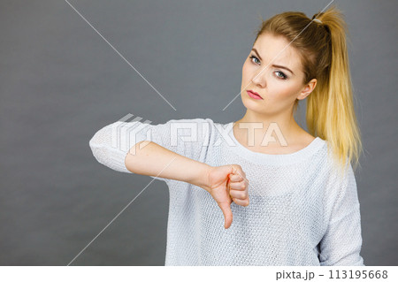 Sad woman showing thumb down gesture Sad woman showing thumb down gesture 113195668