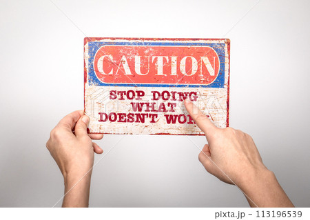 Stop Doing What Doesn't Work. Metal warning sign in a woman's hand on a white background 113196539