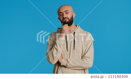 Middle eastern person thinking about a thing on camera, acting pensive and puzzled while trying to make a decision. Arab guy acting thoughtful and unsure about a question. Camera 1. Middle eastern person thinking about a thing on camera, acting pensive and puzzled while trying to make a decision. Arab guy acting thoughtful and unsure about a question. Camera 1. 113198309