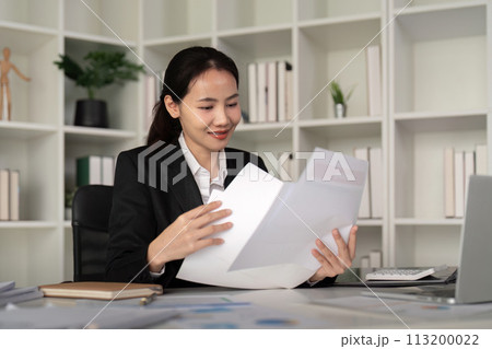 Young business woman asian or employee accounting bookkeeping documents checking financial data or marketing report working in office with laptop. Paperwork management Young business woman asian or employee accounting bookkeeping documents checking financial data or marketing report working in office with laptop. Paperwork management 113200022