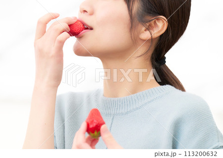 手づかみでイチゴを食べる女性の口元 113200632