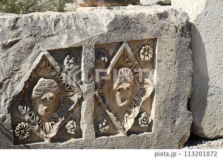 Historical stone bas-relief with carved faces in ancient city of Myra on sunny day. Dead civilization. Ruins of rock tombs in Lycia region, Demre, Antalya, Turkiye Historical stone bas-relief with carved faces in ancient city of Myra on sunny day. Dead civilization. Ruins of rock tombs in Lycia region, Demre, Antalya, Turkiye 113201872