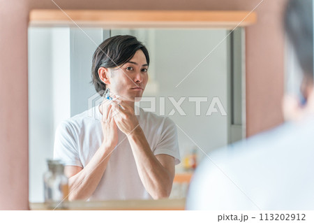 家の洗面所で髭剃りをする若い男性 家の洗面所で髭剃りをする若い男性 113202912