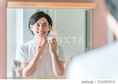 家の洗面所で髭剃りをする若い男性 113202913