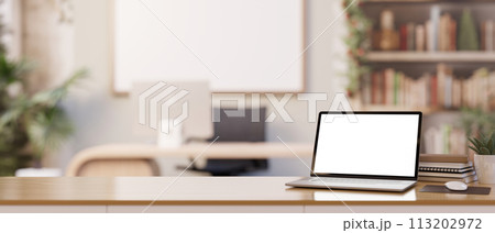 A white-screen laptop computer mockup on a wooden desk in a contemporary new office. A white-screen laptop computer mockup on a wooden desk in a contemporary new office. 113202972