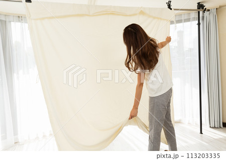 布団カバーを部屋干しする女性. 布団カバーを部屋干しする女性. 113203335