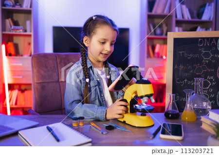 Little girl in denim shirt learning science in evening at home. 113203721